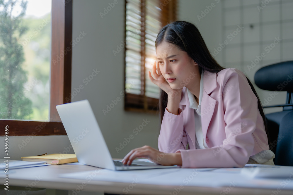 Portrait of business owner, woman using computer and financial statements Anxious expression on expanding the market to increase the ability to invest in business Portrait of business owner, woman using computer and financial statements Anxious expression on expanding the market to increase the ability to invest in business