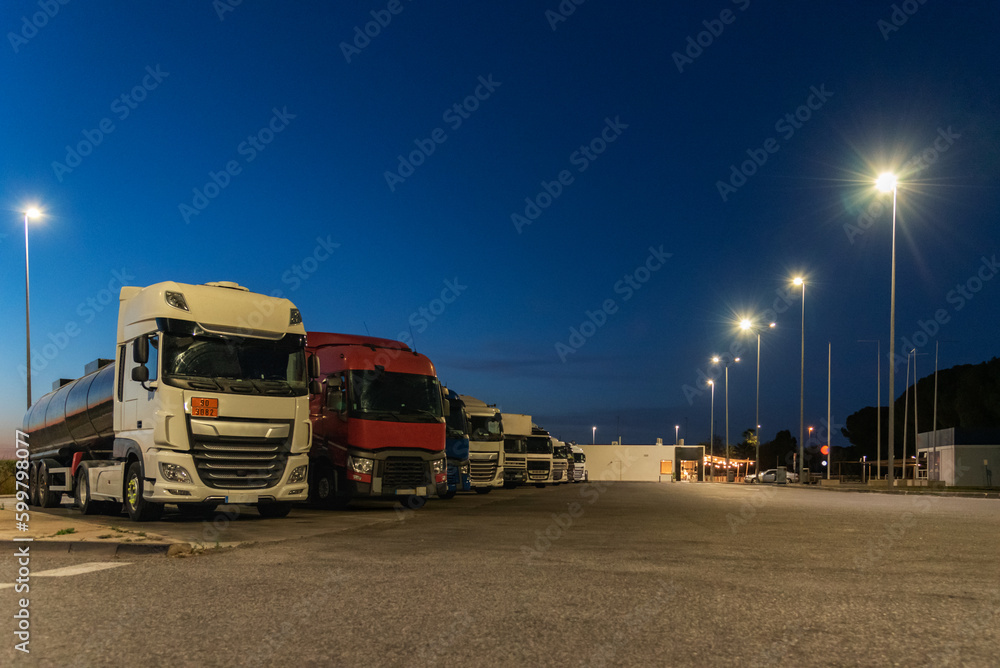 Trucks resting in a highway service area at night, mandatory daily rest.