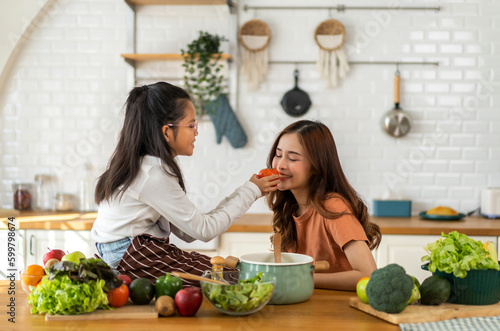 Portrait of enjoy happy love asian family mother with little asian girl daughter child help cooking food healthy eat with fresh vegetable testing smell soup in a pot with spoon.helping mommy 