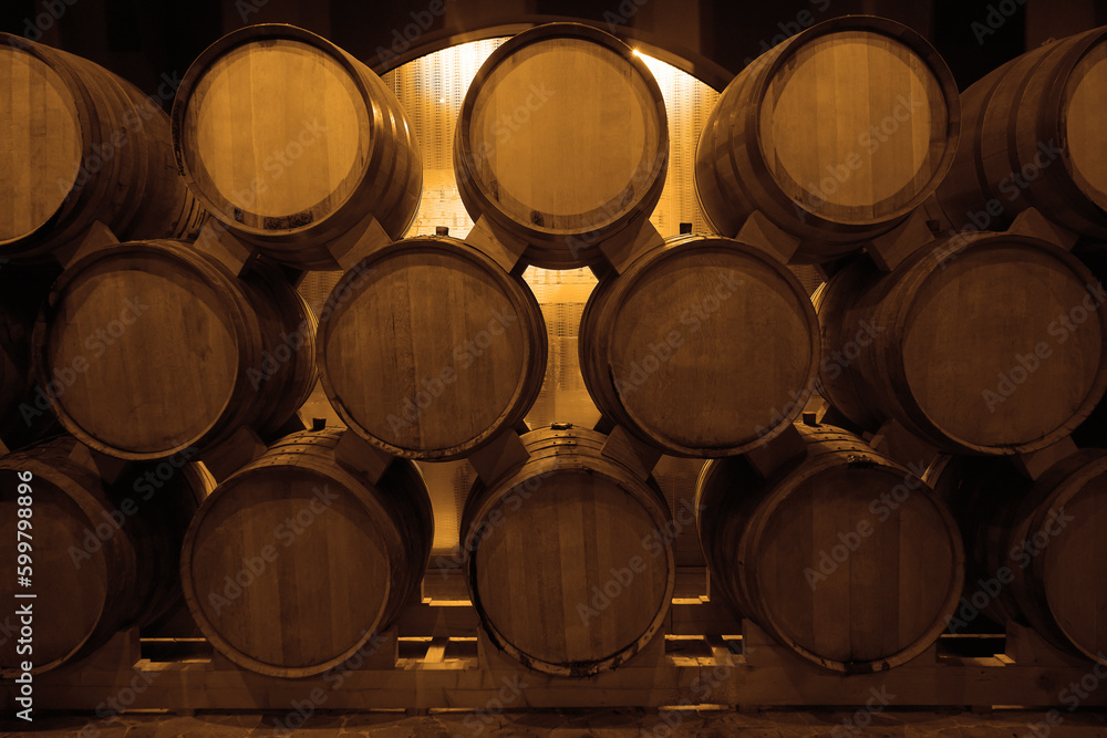 oak wooden Wine barrels in a old, dark wine cellar. front view. Cognac store basement of wooden brandy, beer. Wine storage vault. row of stacks of whisky barrels, set down to mature, in warehouse.