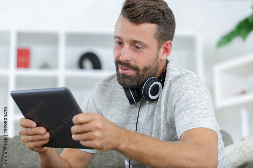 man on sofa with headphones using digital tablet man on sofa with headphones using digital tablet