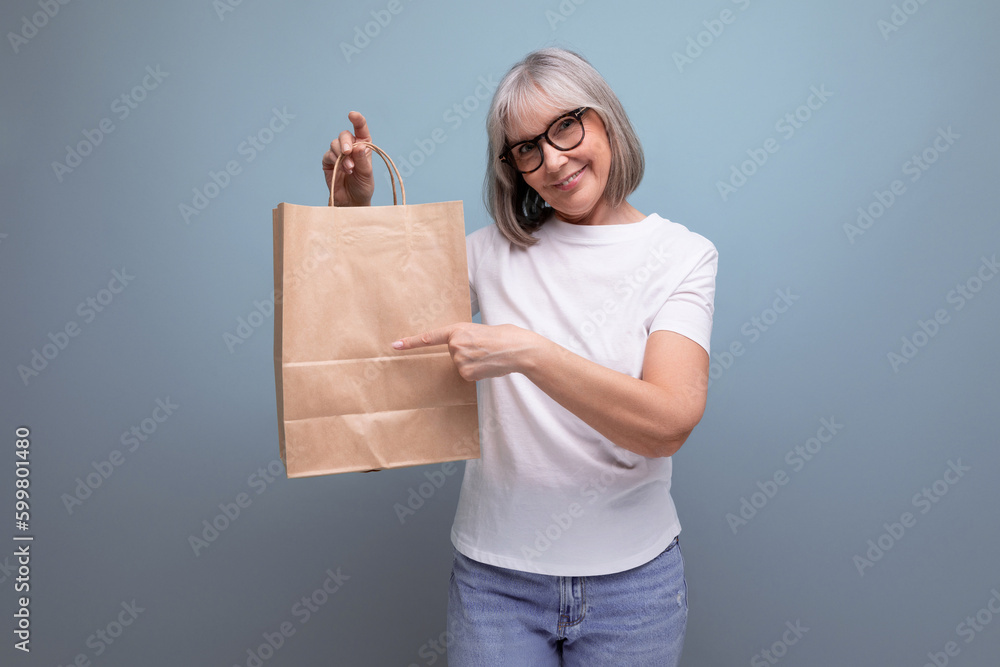 confident 60s woman with gray hair holding pensioner social security package in studio background confident 60s woman with gray hair holding pensioner social security package in studio background