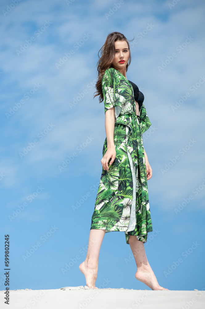 Attractive slender girl in green swimwear posing on white sand beach. Young woman in bikin rests on vacation at sandy ocean shore. Concept travel, swimsuit Attractive slender girl in green swimwear posing on white sand beach. Young woman in bikin rests on vacation at sandy ocean shore. Concept travel, swimsuit