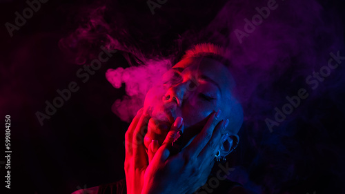 Foto Sensual portrait of asian woman with short haircut smoking in neon light