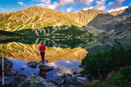 Beautiful summer landscape by a mountain lake. A woman on a stone against the background of the High Tatras in Poland.