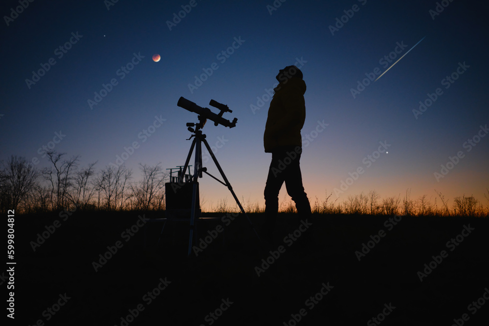 Astronomer looking at the starry skies, planets, meteor shower and lunar eclipse with a telescope.