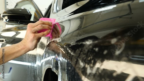 Close up to PPF installation process on a front headlight and hood. PPF is a Paint Protection Film which protect paint from scratches and stone chips. Concept of: Guard, Protect, Car, New, Work.	
