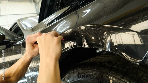 Close up to PPF installation process on a front headlight and hood. PPF is a Paint Protection Film which protect paint from scratches and stone chips. Concept of: Guard, Protect, Car, New, Work.	
