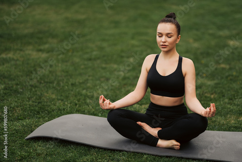 Pretty young woman doing yoga exercise in the park. © JJ Studio