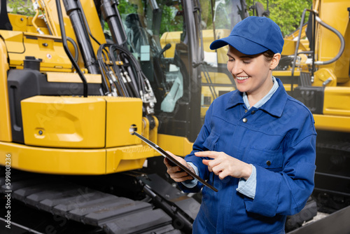 Woman with digital tablet on the background of construction machines 