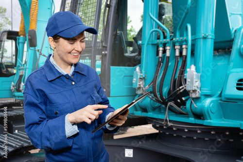 Woman with digital tablet on the background of construction machines	