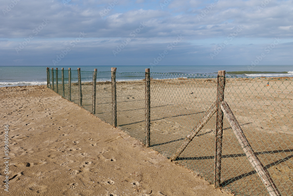 Deserted and Desolate Beach in Winter Time - Wooden Poles with Dividing Net Deserted and Desolate Beach in Winter Time - Wooden Poles with Dividing Net