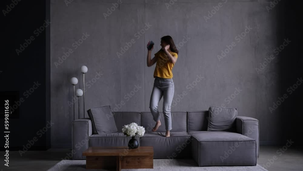 Young woman dance on the couch in living room Young woman dance on the couch in living room