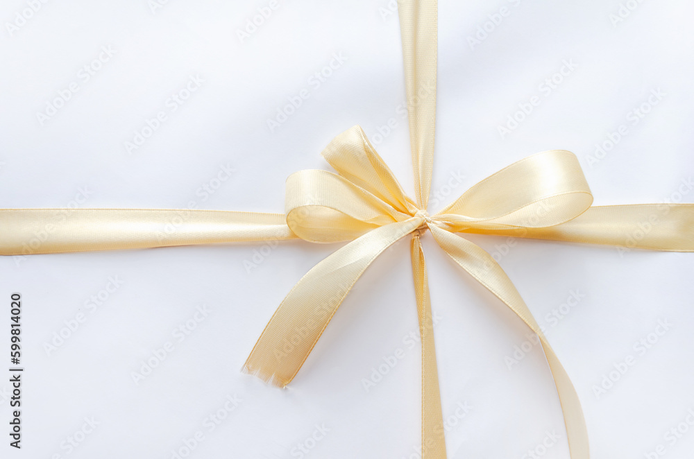 gift is tied with beige ribbon. Flat lay, space text. golden ribbon, bow, crossed, isolated on white gift is tied with beige ribbon. Flat lay, space text. golden ribbon, bow, crossed, isolated on white