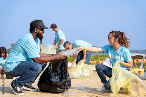 group of diverse volunteers charitable working together to clean up river beach, senior adult and girls picking trash into garbage bags separating reused plastic for recycling waste management