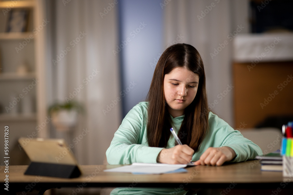 Little girl doing homework with digital tablet. Elementary school student studying online Little girl doing homework with digital tablet. Elementary school student studying online