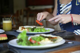 Woman eating vegetarian tortilla wrap with green salad in the restaurant 