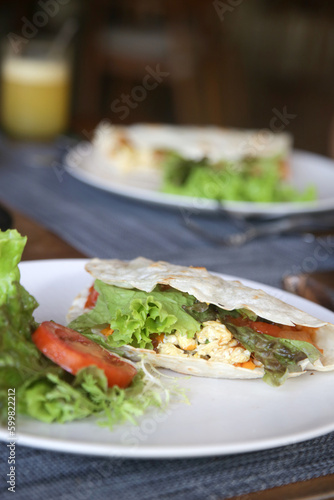 Tortilla wrap portion with green salad served on the restaurant table