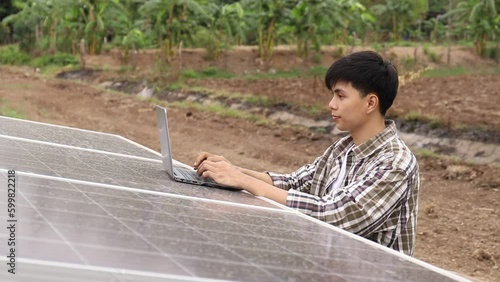 Asian man is using laptop to check solar cell replacement power system. Green energy jobs. Technology. Innovation.