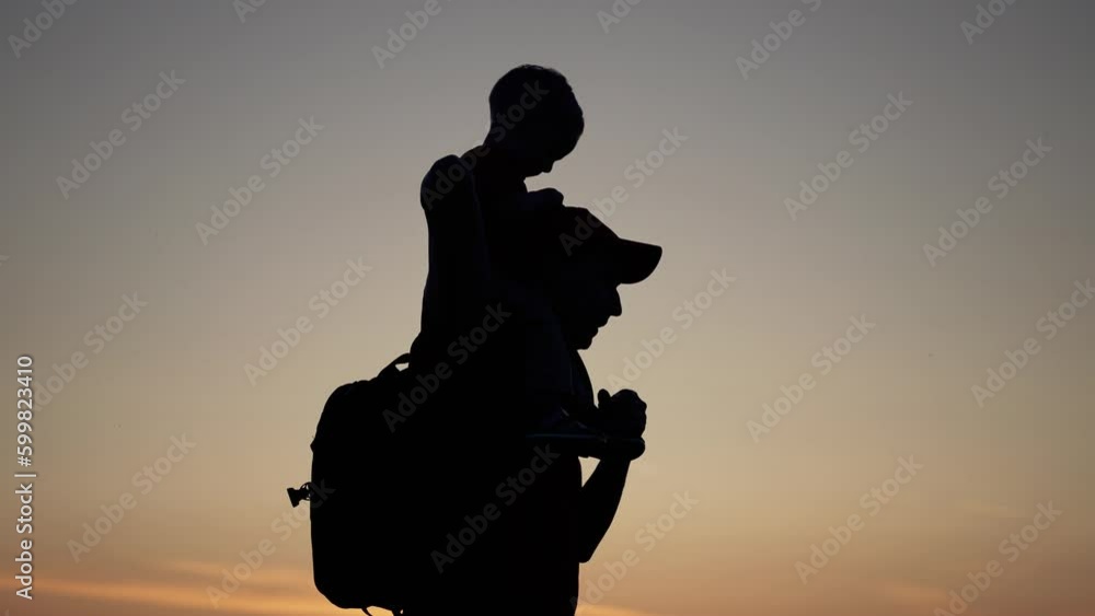 Happy family. Son sitting on neck of the father. Family silhouette in the park. Son plays with his father in the park on vacation. Summer sunset in field. Family holiday concept. Father day in nature. Happy family. Son sitting on neck of the father. Family silhouette in the park. Son plays with his father in the park on vacation. Summer sunset in field. Family holiday concept. Father day in nature.
