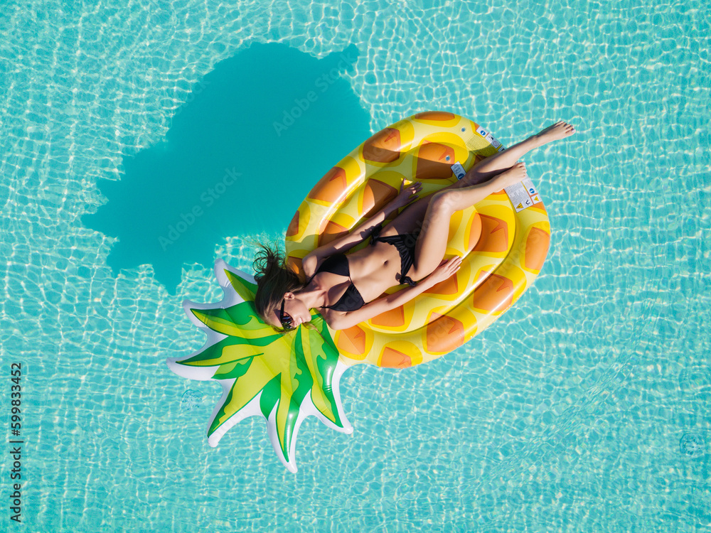Aerial view of female in bikini lying on a floating mattress in ...
