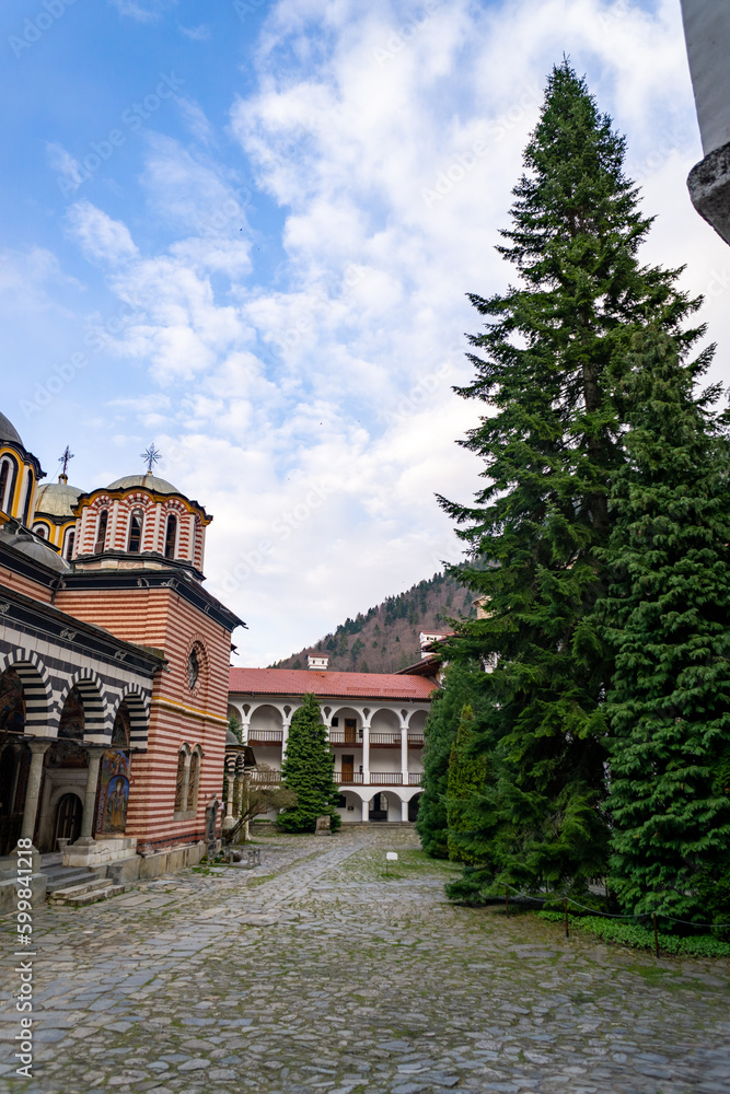 Cloister of the Rila Monastery in Bulgaria, it has many arches and columns, many paintings and frescoes, it is very colorful, photo on a cloudy day.