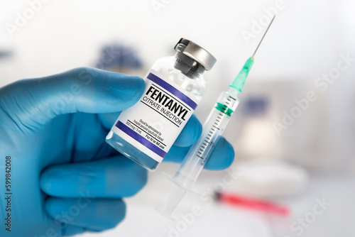 medical professional with vial and injection of dose of Fentanyl Citrate Solution for analgesic treatment. Doctor holding medical injection of medication of Fentanyl is opioid used to palliate pain or photo