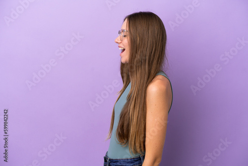 Young Lithuanian woman isolated on purple background laughing in lateral position