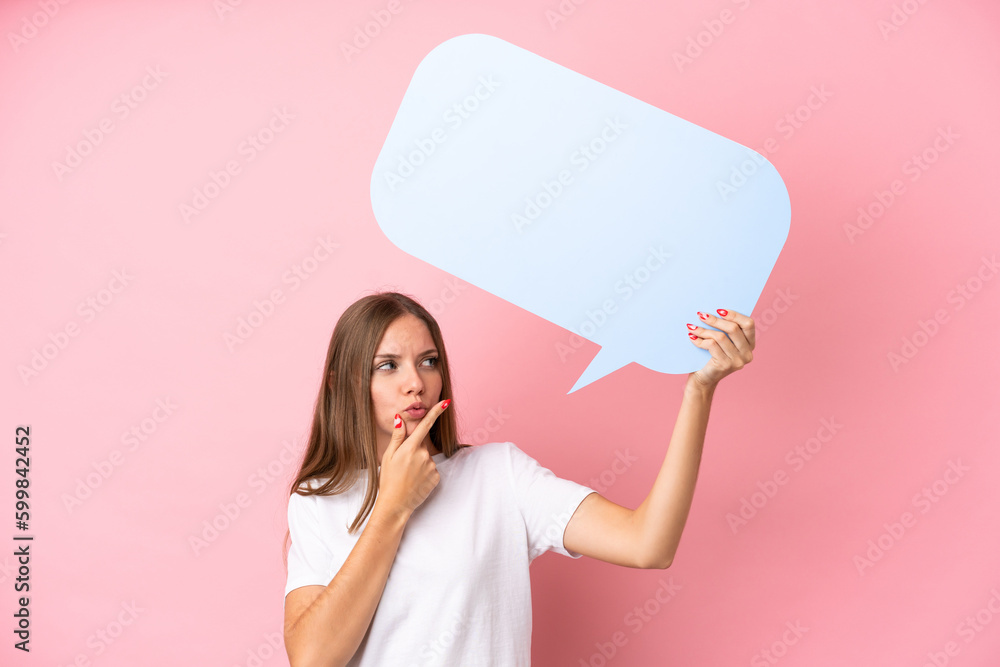 Young Lithuanian woman isolated on pink background holding an empty speech bubble and thinking Young Lithuanian woman isolated on pink background holding an empty speech bubble and thinking