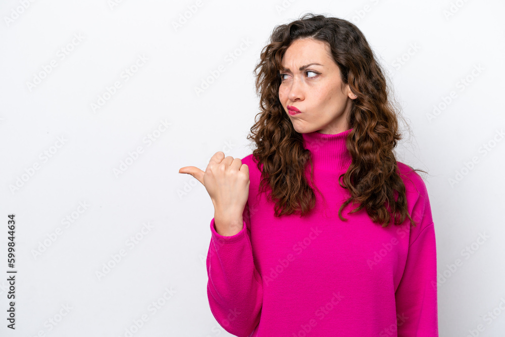 Young caucasian woman isolated on white background unhappy and pointing to the side Young caucasian woman isolated on white background unhappy and pointing to the side