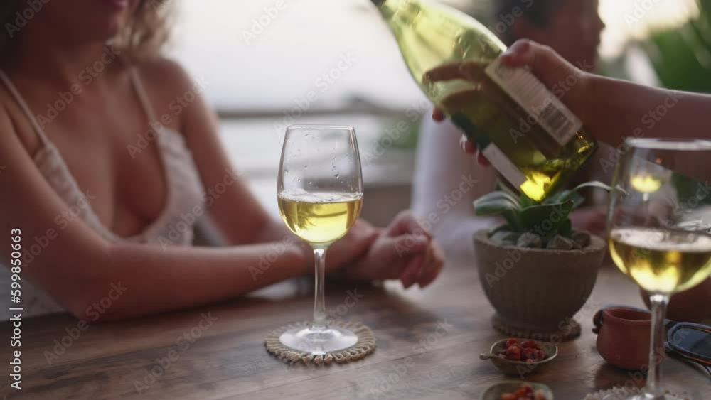 Woman fill glasses of her friends pouring white wine in sea view restaurant. Female hands hold bottle of alcohol drink celebrating birthday, New Year, hen party in bar close-up. Girls night out. Woman fill glasses of her friends pouring white wine in sea view restaurant. Female hands hold bottle of alcohol drink celebrating birthday, New Year, hen party in bar close-up. Girls night out.