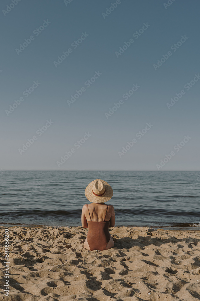 Pretty woman sitting on beach sand and watching at sea and sky. Minimal ...