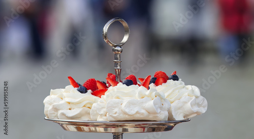 Pavlova desserts embellished with summer berries fruits, raspberries, strawberries and blueberries, closeup.