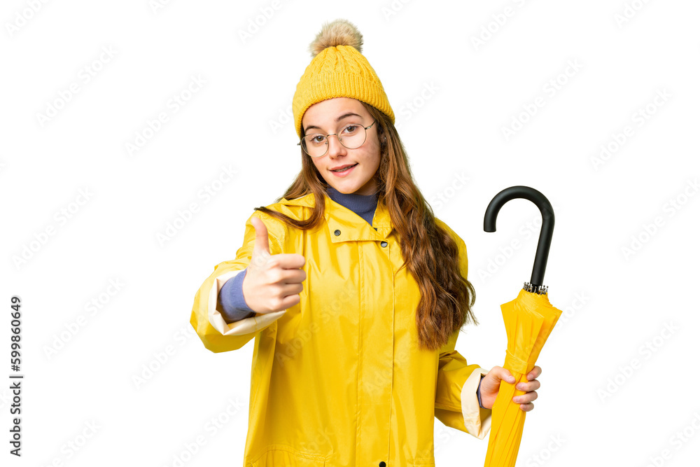Teenager girl with rainproof coat and umbrella over isolated chroma key background with thumbs up because something good has happened Teenager girl with rainproof coat and umbrella over isolated chroma key background with thumbs up because something good has happened