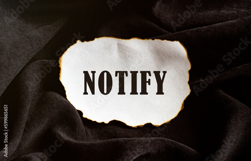 Burned paper on a black background with text NOTIFY