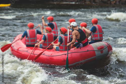 Red raft boat during whitewater rafting extreme water sports on water rapids, kayaking and canoeing on the river, water sports team with a big splash of water