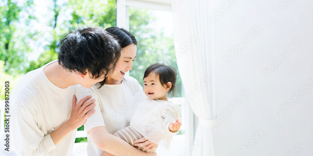 新緑の前で赤ちゃんを抱っこする両親 新緑の前で赤ちゃんを抱っこする両親