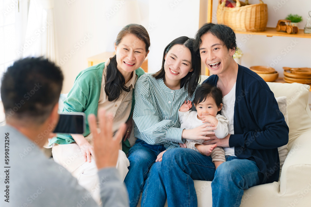 赤ちゃんと家族をスマホで撮影するおじいちゃん