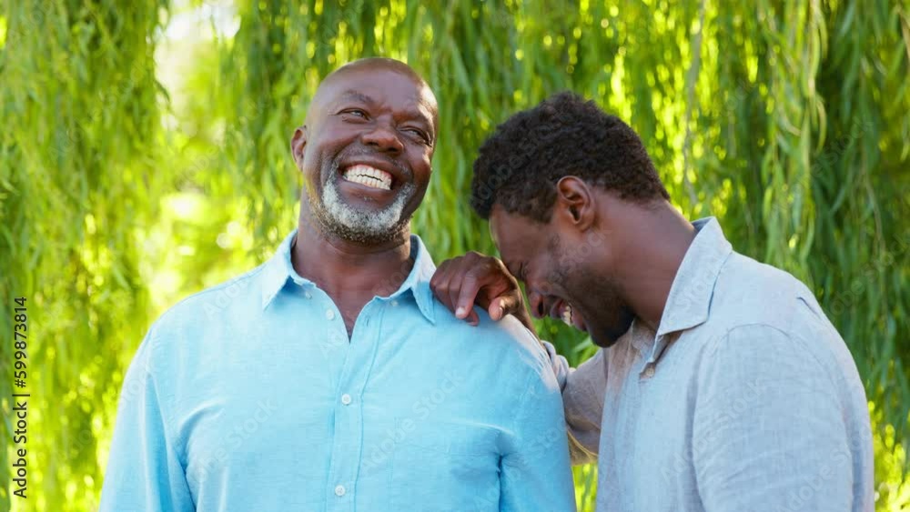 Multi-generation family with senior father and adult son standing outside in garden, park or countryside laughing together- shot in slow motion Multi-generation family with senior father and adult son standing outside in garden, park or countryside laughing together- shot in slow motion
