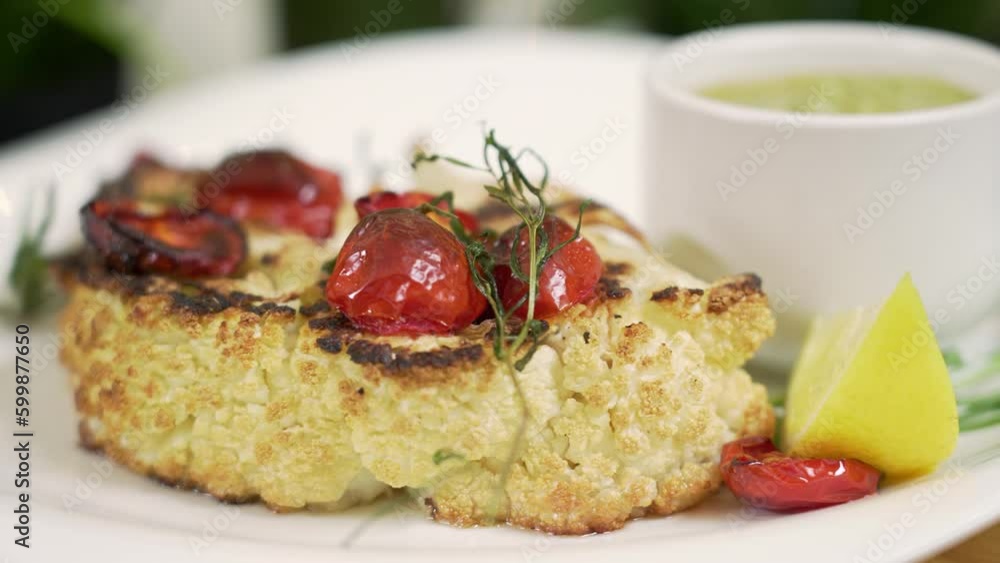 Serving roasted cauliflower steak with cherry tomatoes Serving roasted cauliflower steak with cherry tomatoes