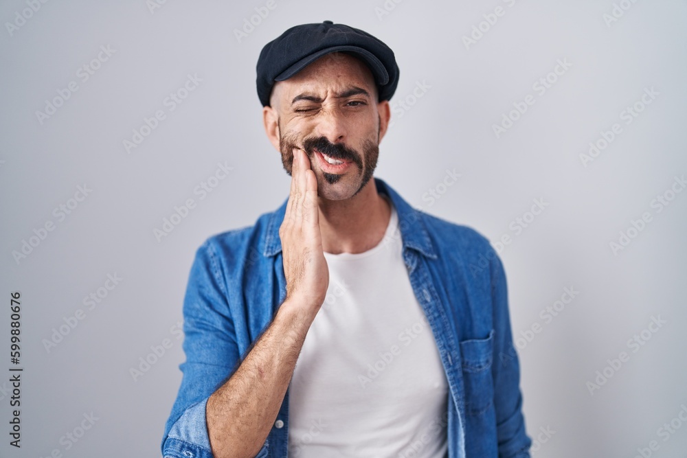 Hispanic man with beard standing over isolated background touching mouth with hand with painful expression because of toothache or dental illness on teeth. dentist Hispanic man with beard standing over isolated background touching mouth with hand with painful expression because of toothache or dental illness on teeth. dentist