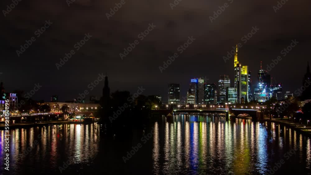 Timelapse of Frankfurt's illuminated skyline, bridge traffic, and city lights reflecting on the river during a partly cloudy autumn night. Timelapse of Frankfurt's illuminated skyline, bridge traffic, and city lights reflecting on the river during a partly cloudy autumn night.