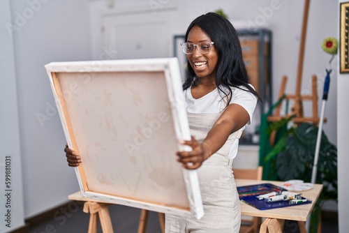 Young african american woman artist smiling looking draw at art studio