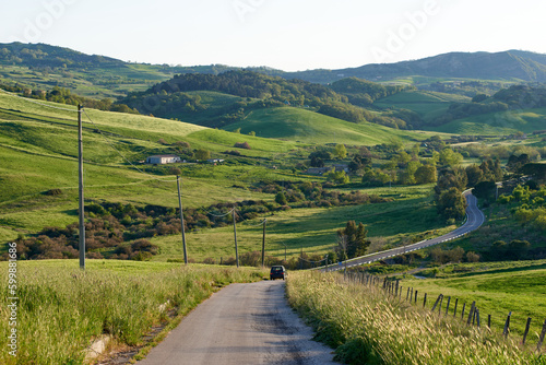 a car travels down a road that leads to a lush green valley