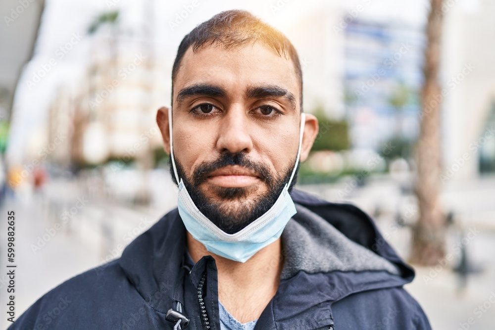 Young hispanic man wearing medical mask standing at street Young hispanic man wearing medical mask standing at street