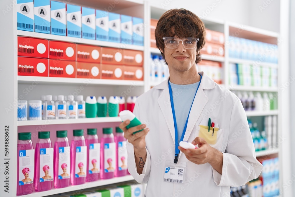 Young blond man pharmacist holding toothpaste bottle at pharmacy Young blond man pharmacist holding toothpaste bottle at pharmacy