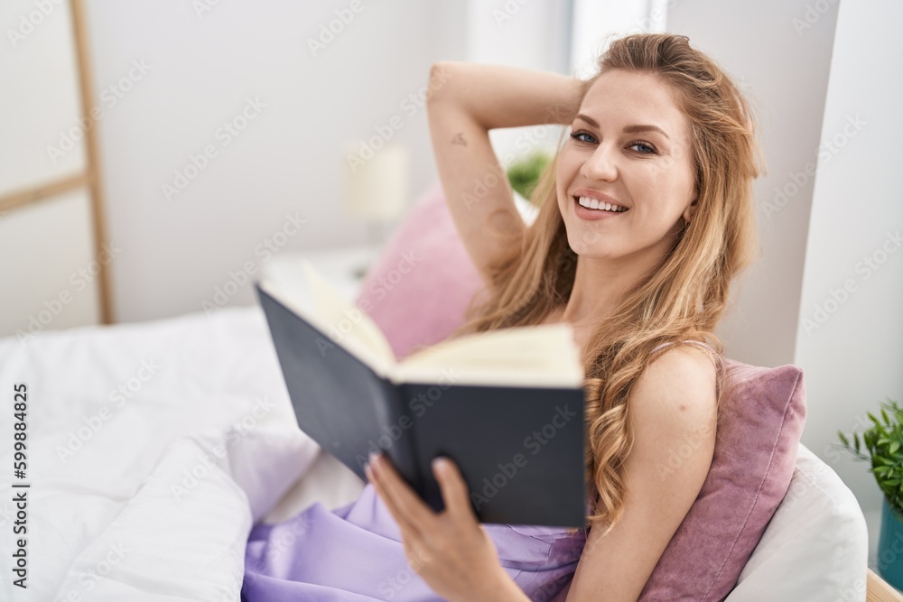 Young blonde woman reading book sitting on bed at bedroom Young blonde woman reading book sitting on bed at bedroom