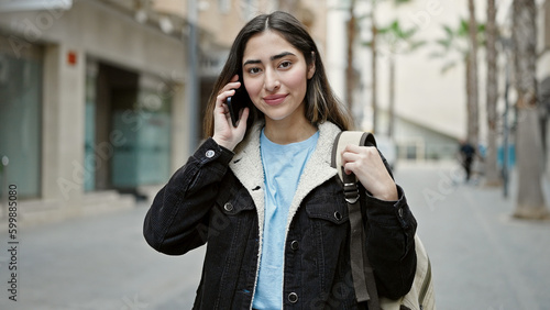 Young beautiful hispanic woman student smiling confident talking on smartphone at street © Krakenimages.com