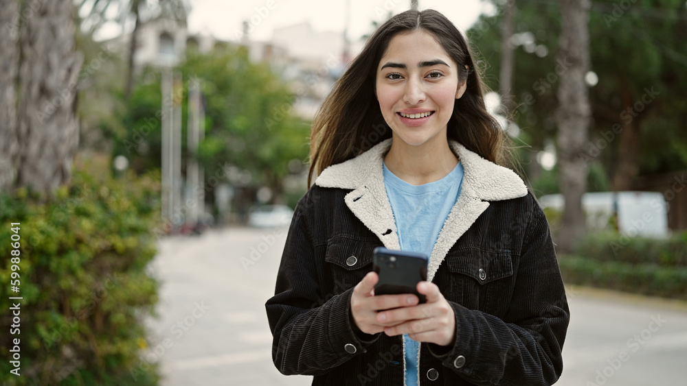 Young beautiful hispanic woman smiling confident using smartphone at park