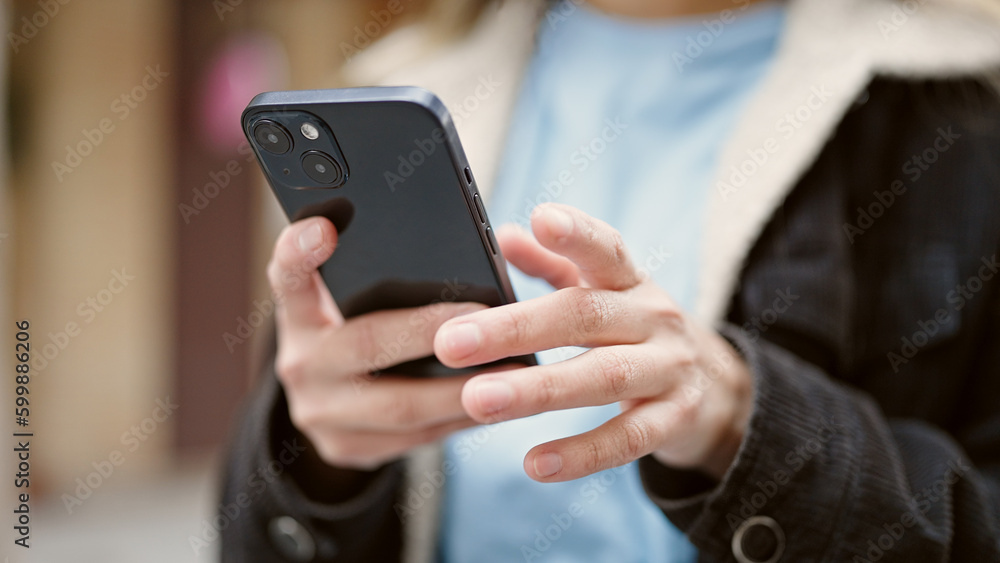 Young beautiful hispanic woman using smartphone at street